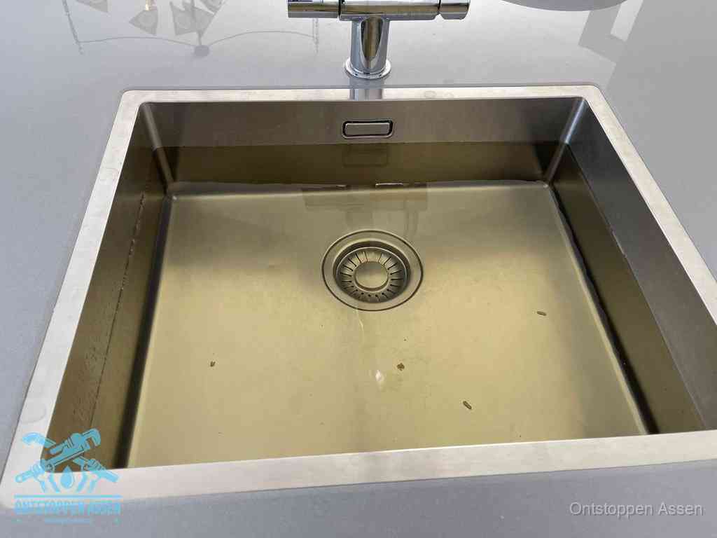 Stilstaand water in een rvs spoelbak dat niet wegloopt, een duidelijk signaal van een gootsteenverstopping in Assen