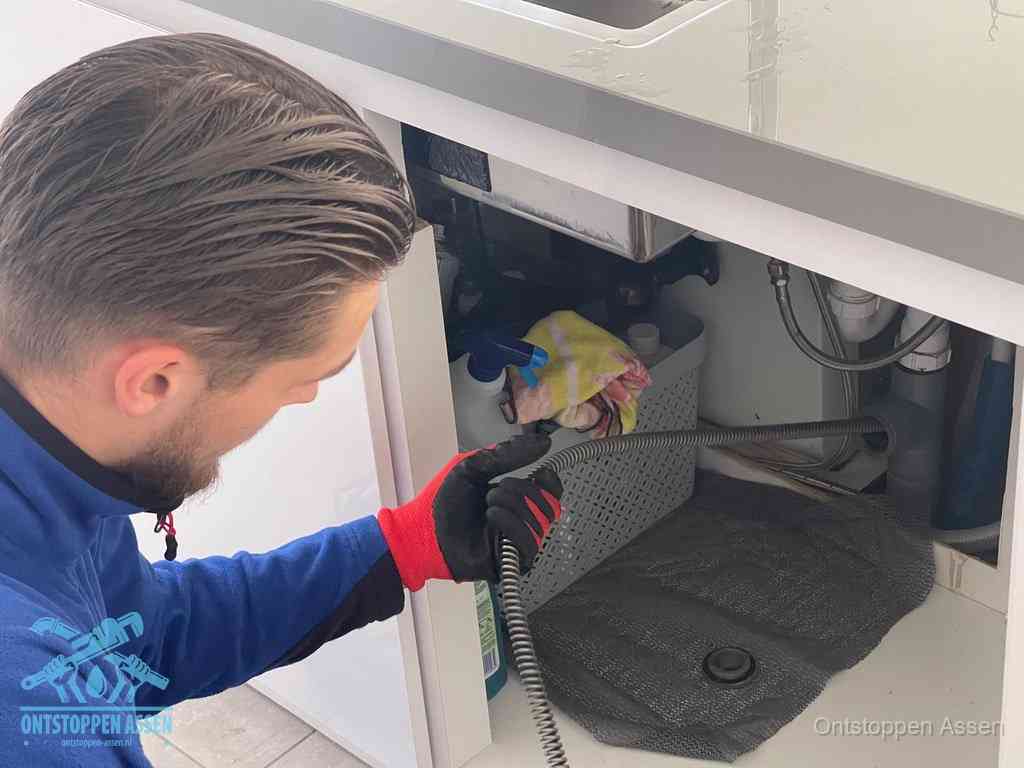 Een monteur voert een flexibele ontstoppingsveer in de afvoer om een verstopping voorbij de bocht van het toilet te bereiken in Assen