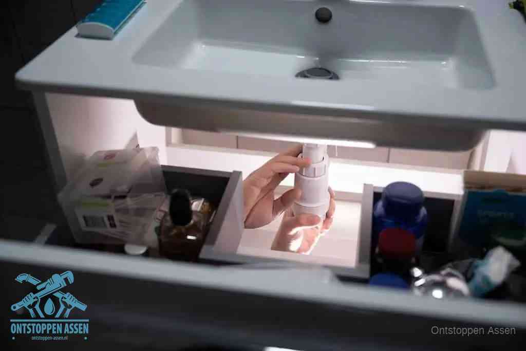 Een pompfles met zeep boven een wastafel in de toiletruimte, de warm water en afwasmiddel-methode om de wc te ontstoppen in Assen