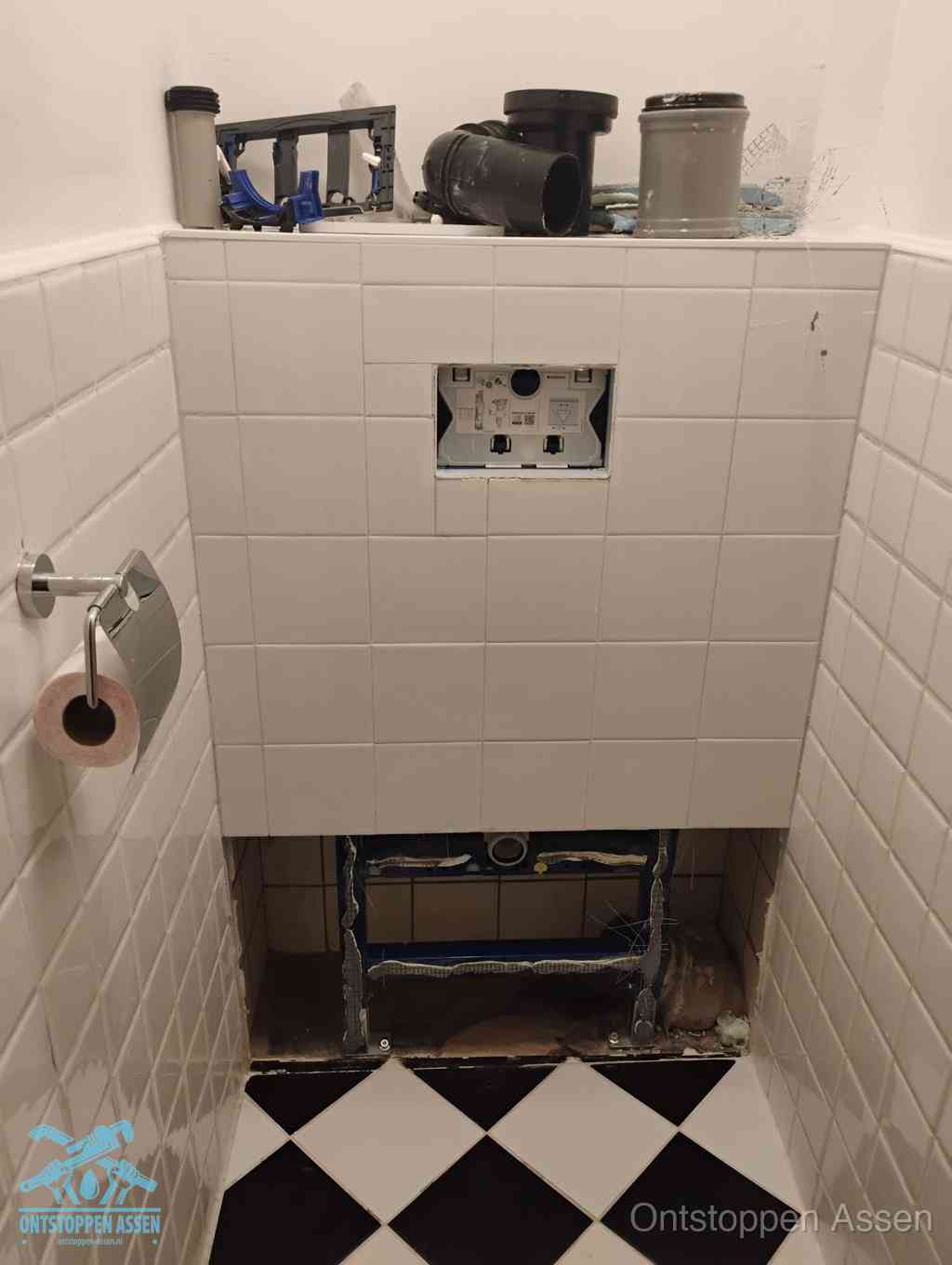 Een toiletruimte waar het hangtoilet en de inbouwreservoir-onderdelen zijn vrijgelegd voor onderhoud, periodiek nazicht voorkomt een wc-verstopping in Assen