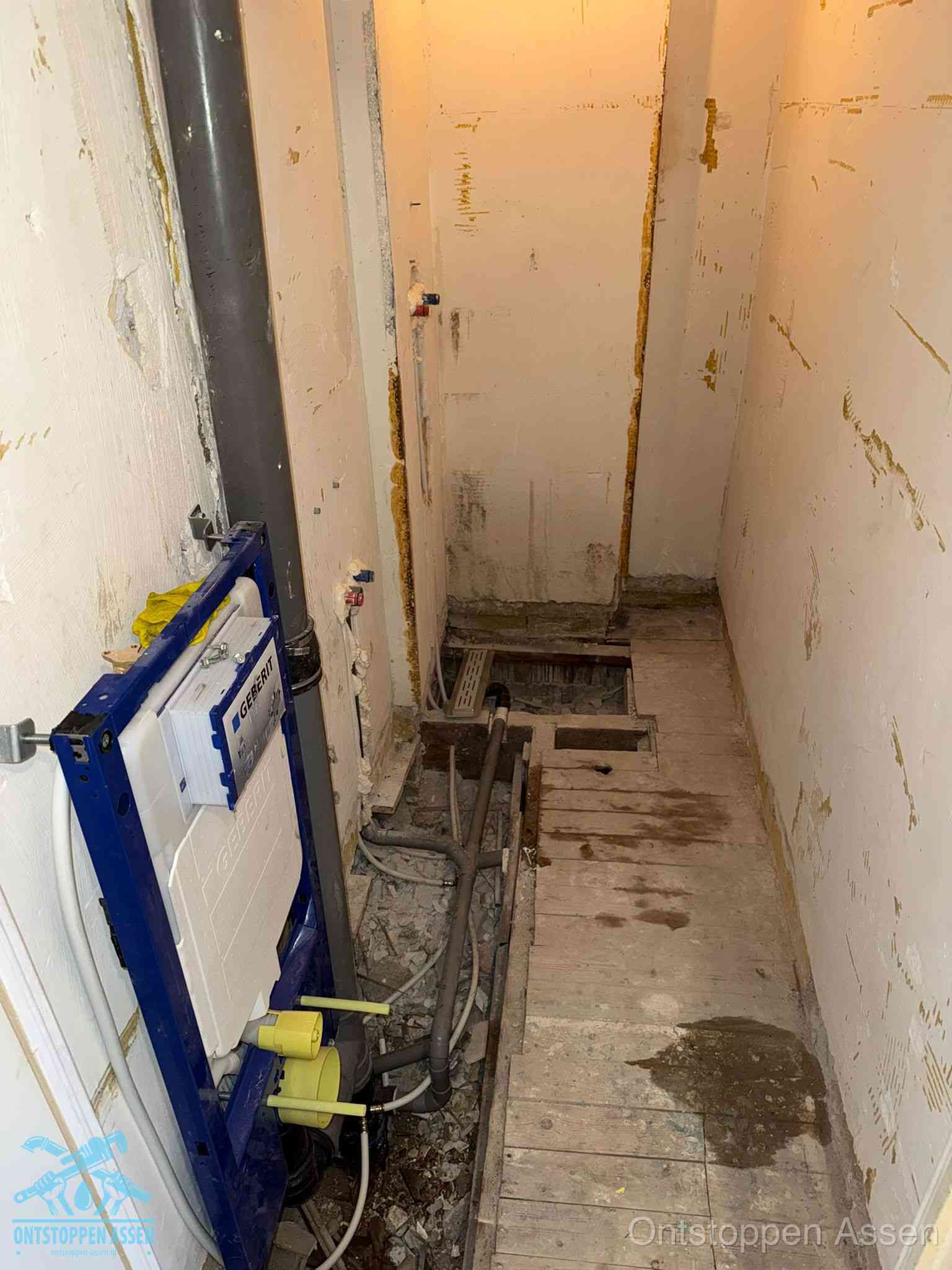 Een opgebroken toiletruimte tijdens renovatie met een Geberit inbouwreservoir en blootliggende oude afvoerleidingen, typisch voor oudere woningen in Assen